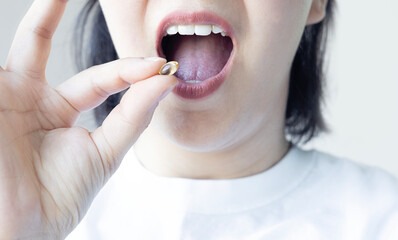 Close up of woman taking fish oil. Omega3  supplament. Healthcare concept