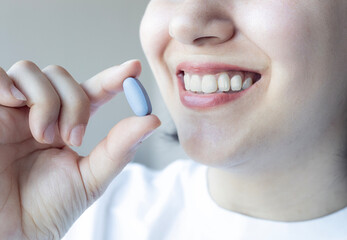 Close up of woman smiling and holding pill. Taking medicine. Healthcare concept