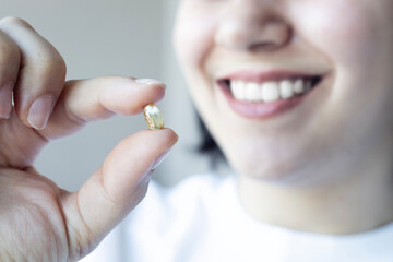 Close up of woman smiling and taking fish oil. Omega3  supplament. Healthcare concept