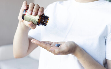 Woman holding medicine bottle and taking pill	