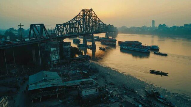 Wide angle drone shot, crowded traffic passing over Calcutta's iconic 'Howrah Bridge' and the Hooghly River flowing underneath. 