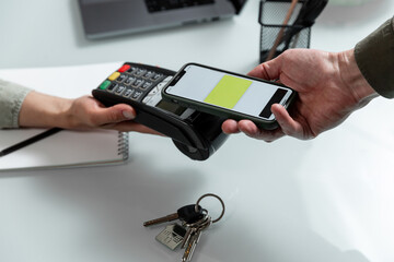 Hands using pos terminal  and smart phone to complete nfc payment during real estate  financinal operation.