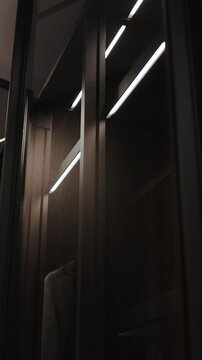 Close-up of a woman's hand taking a dress out of the closet. Elegant closet design that effectively displays modern fashion items and accessories. Vertical video