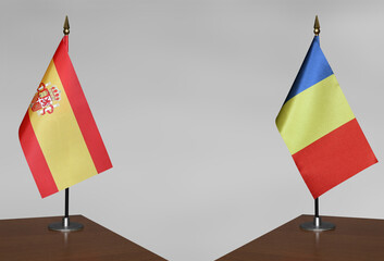 Table flags of Romania and Spain on a gray blurred background