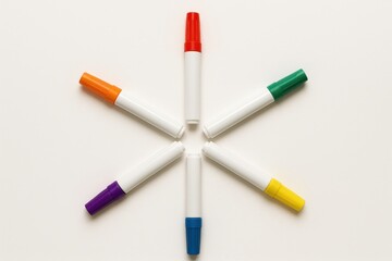 Markers with lids of different colors, lying on a white background in the shape of a star