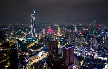 Obraz premium Aerial view of Kuala Lumpur city skyline at night with glowing skyscrapers and illuminated roads