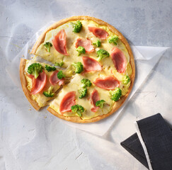 Pizza mit Schinken und Brokkoli auf Betonfond als Topshot, Italien, Käse, Slice, Pizza, 