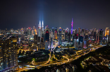 Aerial view of Kuala Lumpur city skyline at night with glowing skyscrapers and illuminated roads