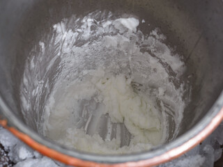 Close-up of a creamy white ice cream within a metal churn, nestled on a bed of ice