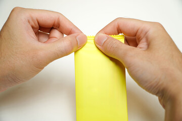 man's hand holding yellow condom isolated on white background