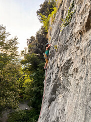 Female Climber Leading A Route In Yellow Pants At Nago Rock Climbing Area Near Arco, Lake Garda, Italy
