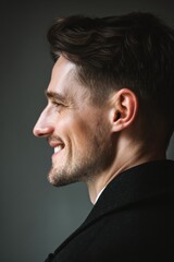 Fototapeta premium Side view of a smiling, handsome man in a dark coat, radiating confidence and charm.