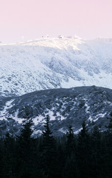 Snowy mountains tower over dark evergreens, calling winter sports lovers to explore