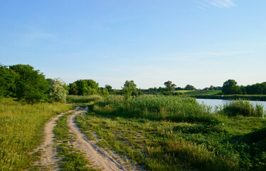 Serene Countryside Path Along Green Fields and a Tranquil Riverbank..