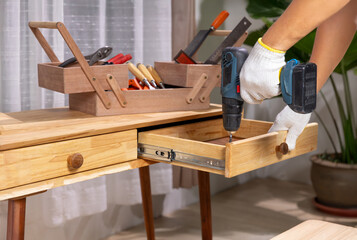 Handyman repair wooden drawer of cabinet in living room.
