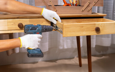 Handyman repair wooden drawer of cabinet in living room.