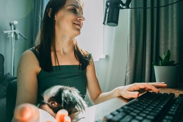 smiling woman engaging in a podcast recording at home office, concept of digital media creation