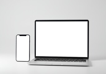 Laptop and smartphone with blank white screens sit side by side on a white surface, showcasing modern technology