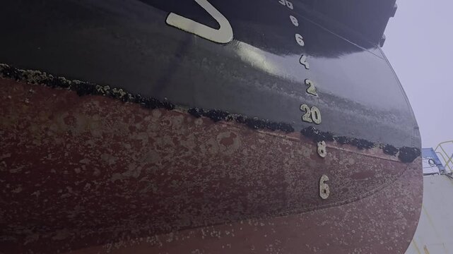 Downward camera view reveals blue mussels and biofouling on ship hull near bow. Needs cleaning work
