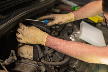 hands of a mechanic repairing the engine of a diesel car in a mechanical workshop