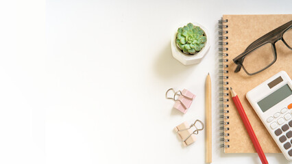 A whitebdesk with a calculator, a pen, a pencil, and a plant. The desk is clean and organized
