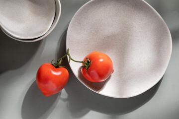 Flat lay of gray monochrome plates and tomatoes. Culinary concept with space for text
