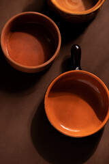 Arrangement of ceramic plates on brown background. Earthenware pottery objects, space for text. 
