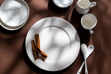 White ceramic dessert plates with cinnamon on brown background. Food concept with space for text
