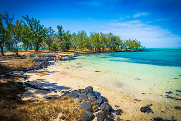 Picturesque view of mother and two children wading through the shallow crystal clear water, exploring the exotic island of L'îlot Bernache, Mauritius © schusterbauer.com