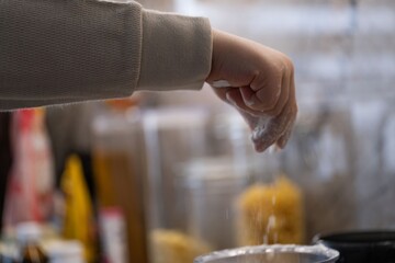 Child Sprinkling Flour from Hand into Bowl