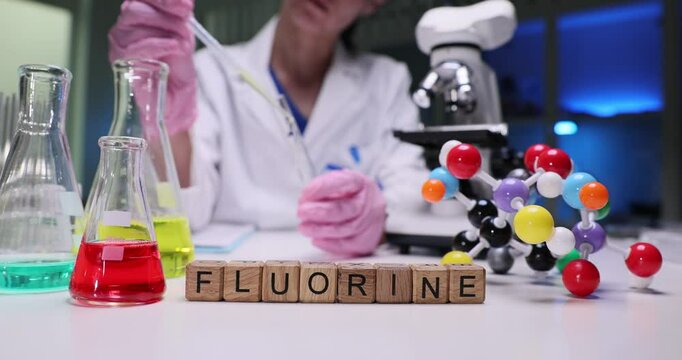 A scientist is conducting indepth fluorine research in a laboratory, utilizing pipettes and various glassware