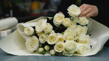 Beautiful white roses in a flower shop. Florist assembles a bouquet to order