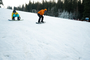 Excitement on the Slopes as Two Snowboarders Enjoy a Winter Day in the Mountains Surrounded by...
