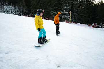 Winter thrill on snowy slopes with snowboarders embracing the cold breeze in a scenic mountain...