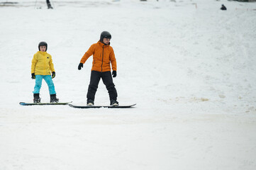 Snowboarding adventure unfolds on a wintery slope as a child and adult embrace the thrill of the...
