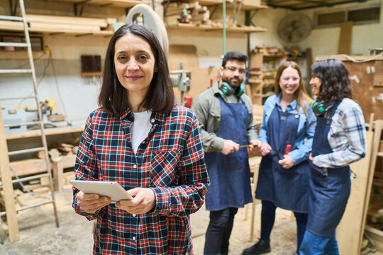 Team working together in a busy woodworking shop - Powered by Adobe