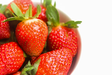 close up of strawberries in a bowl on a white background with negative space
