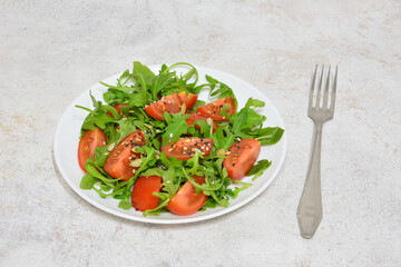 Fresh and Healthy Salad with Tomatoes and Arugula on a White Plate with fork