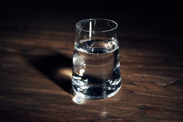 A glass of water is sitting on a wooden table