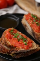 Tasty bread with tomato, parsley and oil on table, closeup