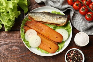 Delicious smoked herring fillets with onions and lettuce on wooden table, flat lay