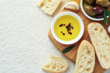 Slices of bread with oil, spices and olives on light table, flat lay. Space for text