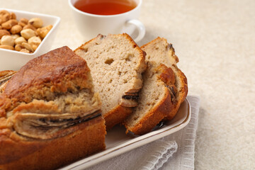 Cut banana bread with nuts and tea on light grey table, closeup