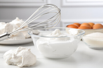 Whisk, whipped cream in bowl and other ingredients on light table, closeup. Cooking meringue cookies