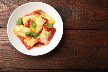 Delicious ravioli with tomato sauce, parmesan cheese and basil on wooden table, top view. Space for text
