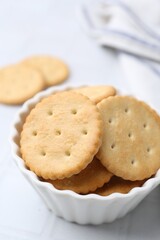 Tasty salty crackers on white tiled table, closeup