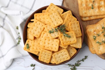Tasty salty crackers and thyme on white table, flat lay