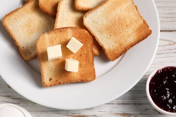 Slices of tasty toasted bread with butter and jam on light wooden table, flat lay