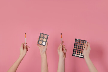 Women with eyeshadow palettes and brushes on pink background, closeup. Space for text