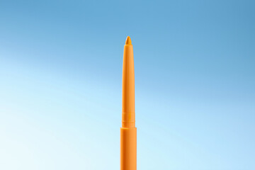 One twist up eye pencil on light blue gradient background, closeup